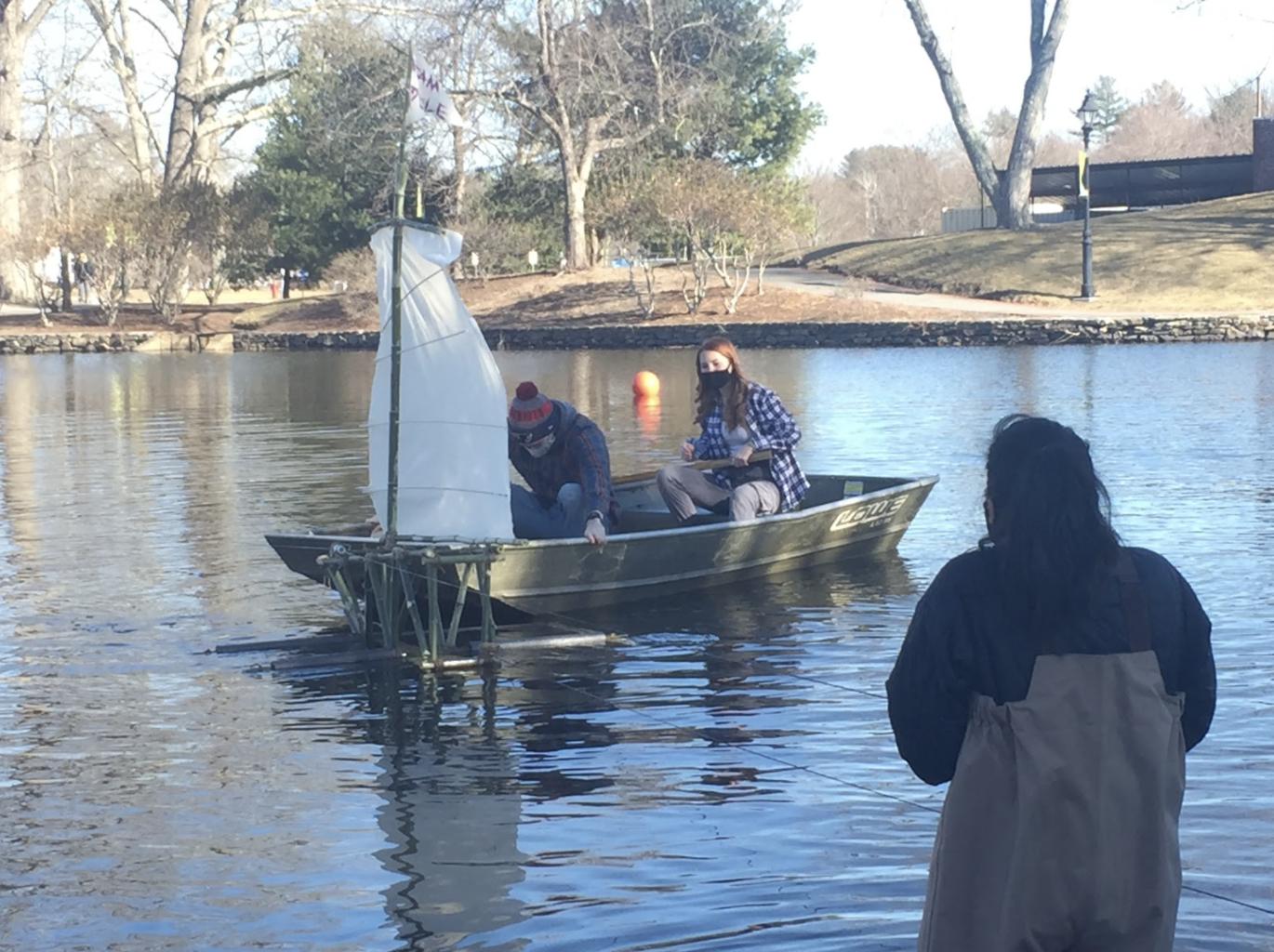 Students in the Public Art class assist by untangling the wires of a bamboo boat