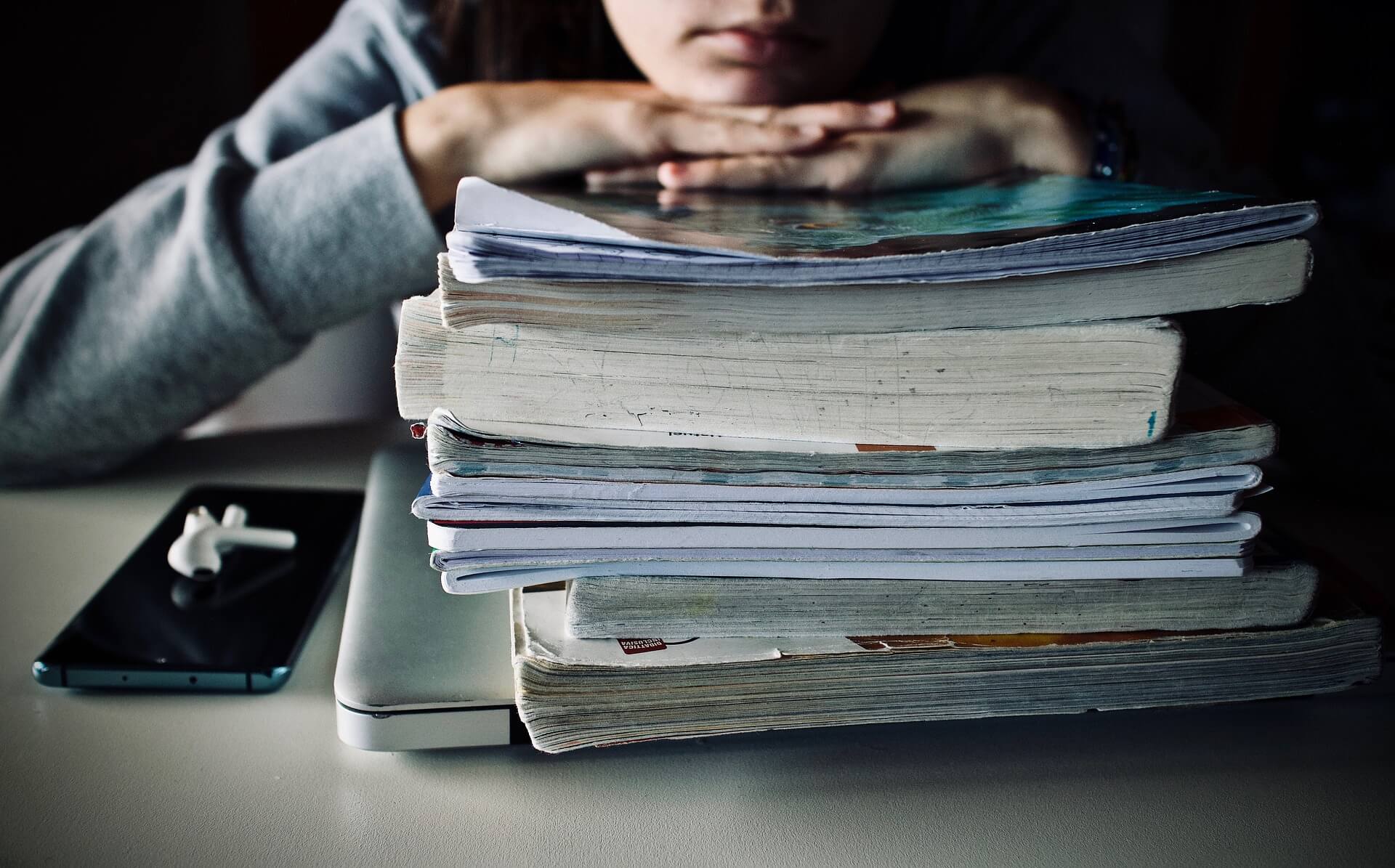 A student resting their head on a stack of textbooks